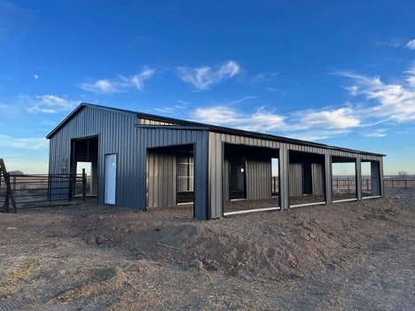 Silverline Structures metal horse barn with large open stalls and dark gray exterior, set against a clear sky with visible moon.