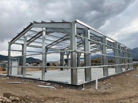 Sturdy metal barn kit in construction phase by Silverline Structures with a mountainous backdrop.
